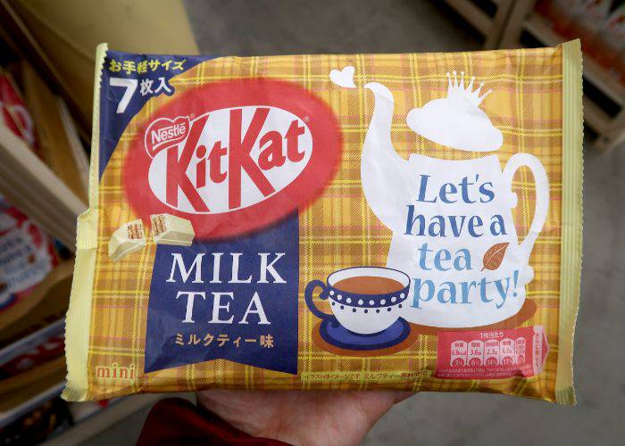 A hand holding a seven-pack of the Royal Milk Tea KitKats,